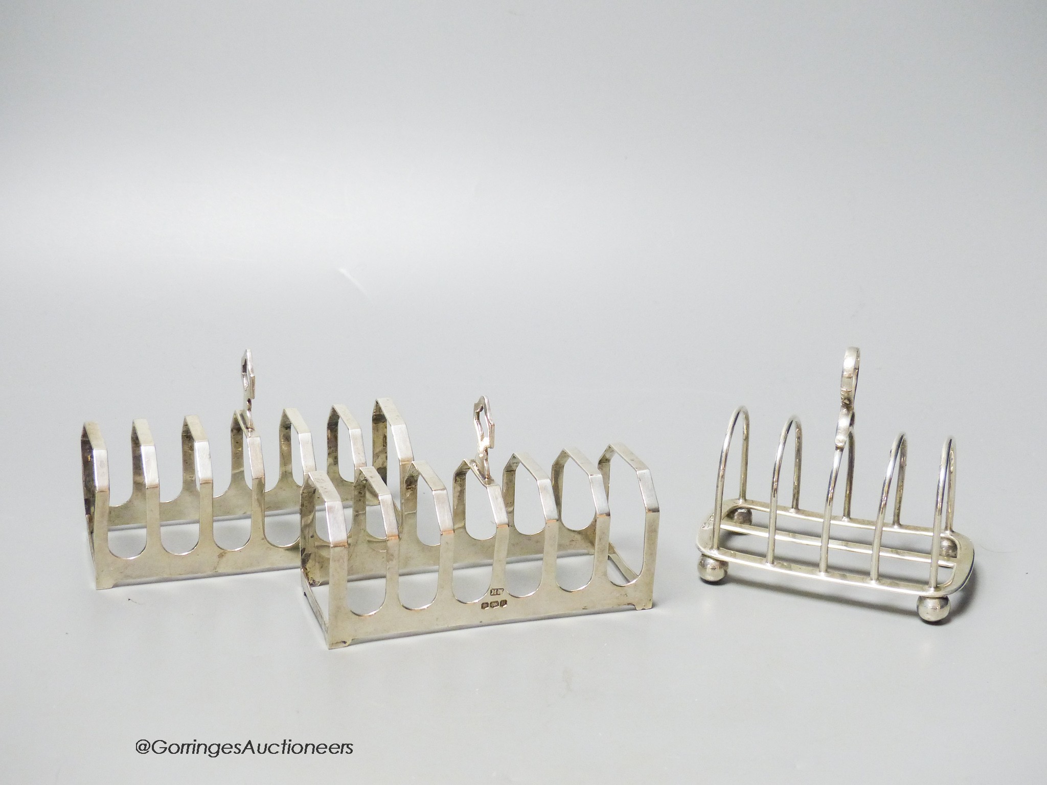 A pair of silver toast racks, Sheffield, 1950, 11.3cm and one other silver toastrack, 7oz.